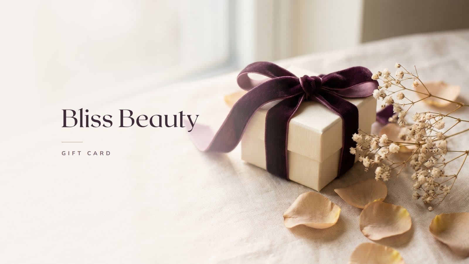 The Bliss Beauty gift card: a cream gift box tied with a plum velvet ribbon, with dried baby's breath and rose petals