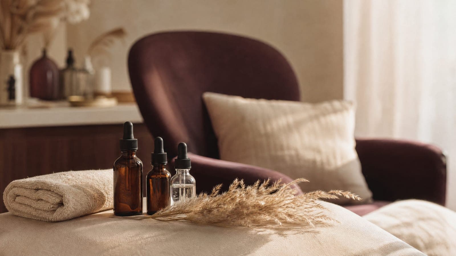 Small glass bottles and a folded towel on warm cream linen